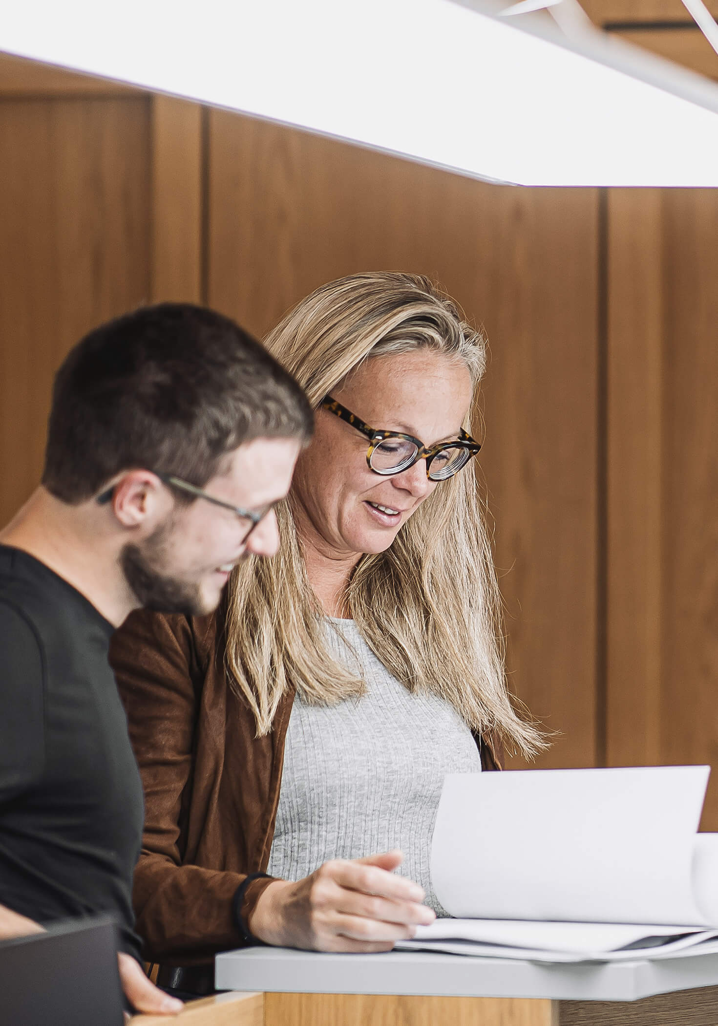 Zwei Arbeitskollegen sehen sich Unterlagen für die Steuerberatung an - Datenverarbeitung Steger